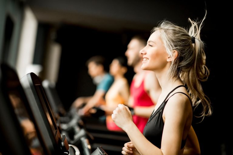 young people running on treadmills in modern gym