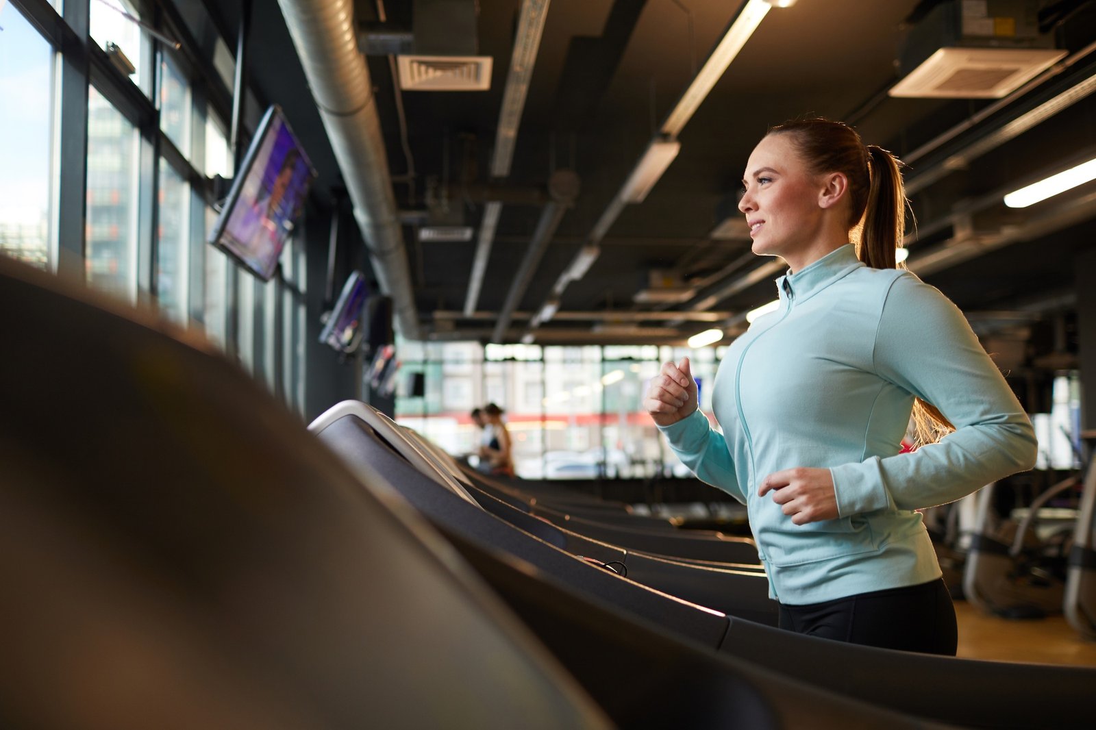 Young Woman on Treadmill in Gym Wide Angle