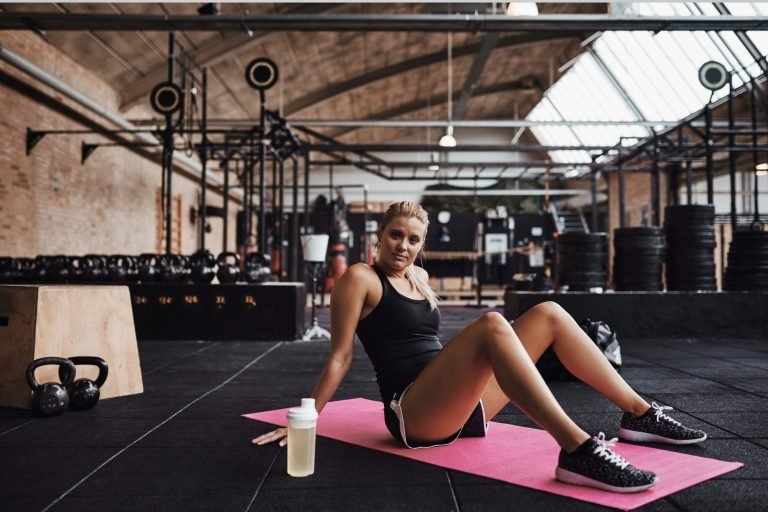 Young woman sitting on a gym floor after working out